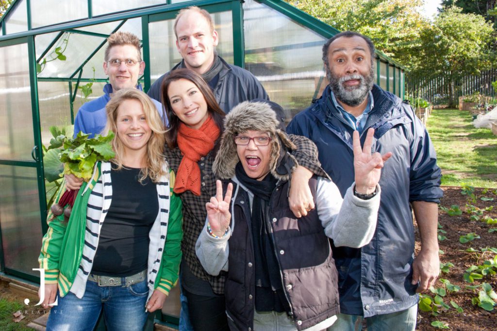 A diverse group of Mind charity volunteers and Rachel de Thame posing happily in a Camden community garden.