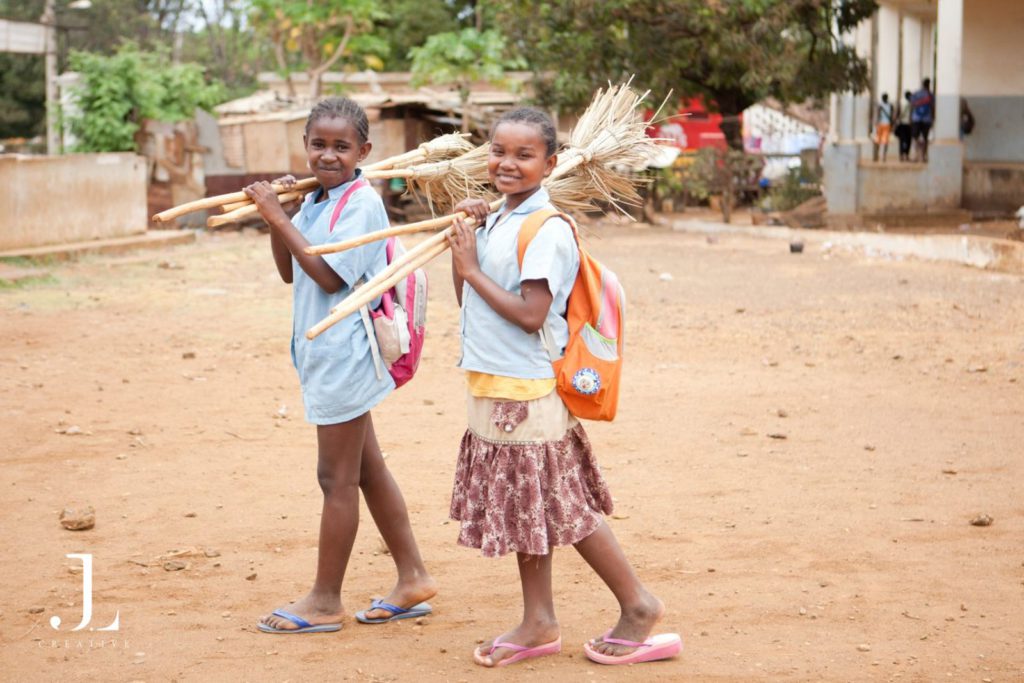two students carrying brooms