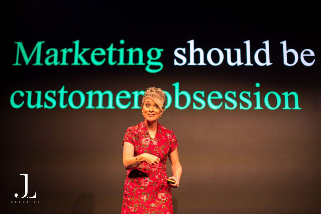 speaker on stage presenting to audience at tech conference