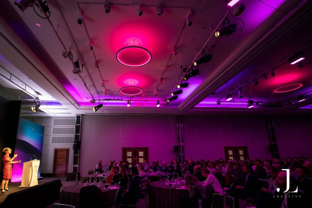 speaker on stage presenting to audience at tech conference