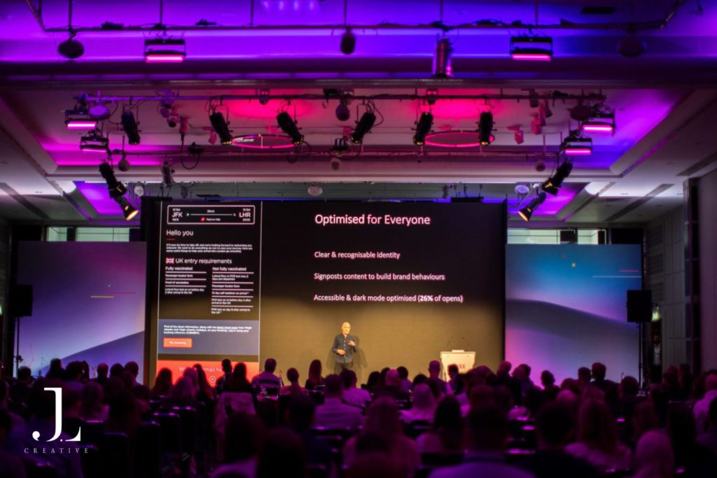 speaker on stage presenting to audience at tech conference