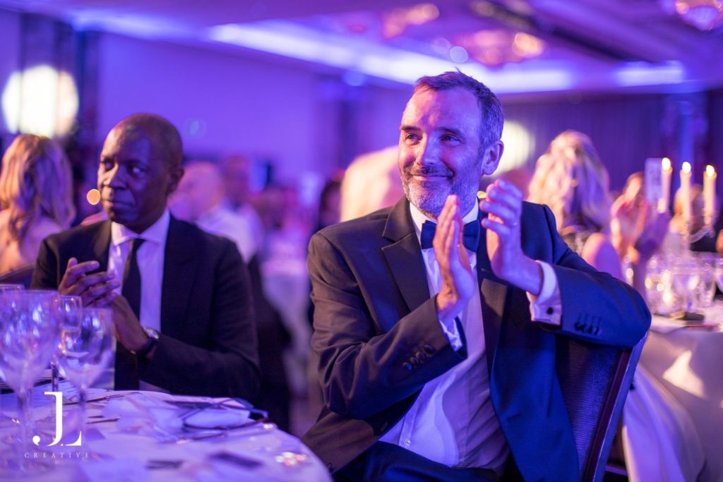 Guest in black tie applauding at a London gala dinner