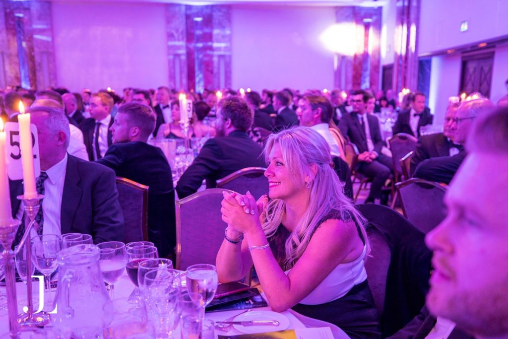 Candid photo of a guest at a formal London gala dinner with purple lighting