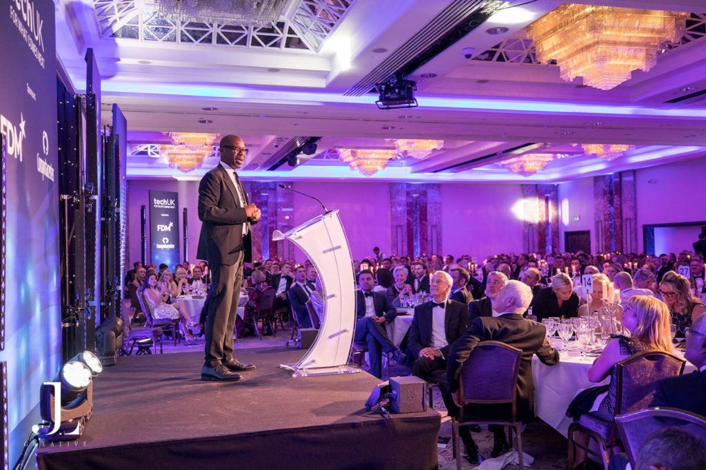 Speaker on stage at a corporate awards ceremony in London