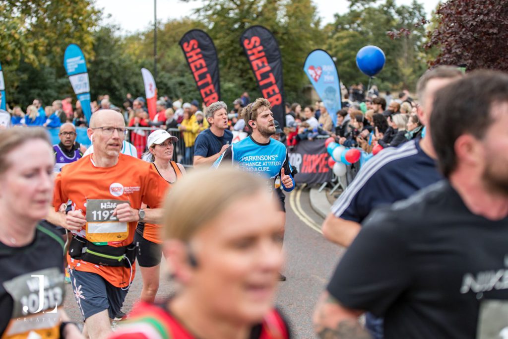 A runner in a Parkinson’s UK vest pushes through a crowd of participants during a charity race.