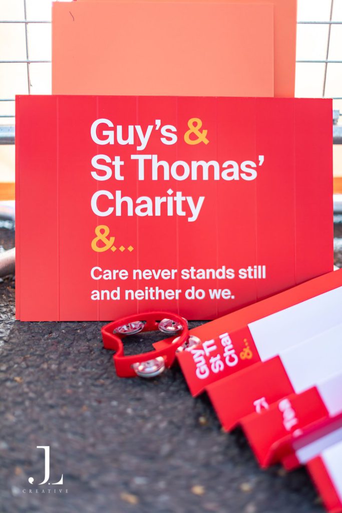 Branded Guy’s & St Thomas’ Charity signage and a red tambourine at a race cheer point