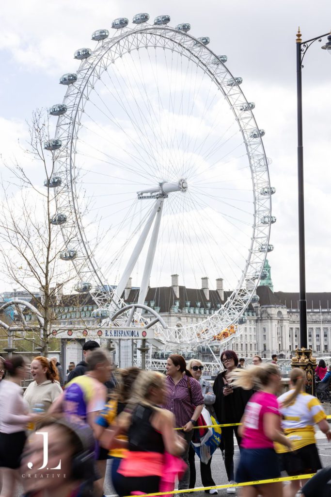 Blurred motion of marathon runners passing the London Eye on a bright day