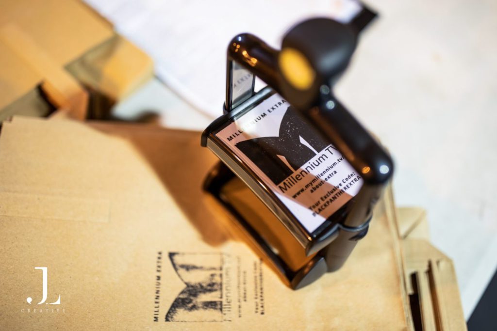 Close-up of Millennium TV branded materials and stamp, London corporate event photographer.