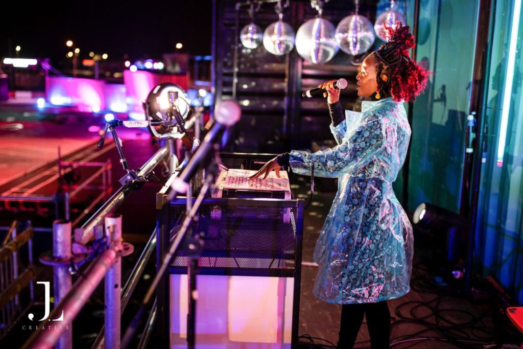 Musician performing at a DJ booth with neon lighting, corporate event photography London.