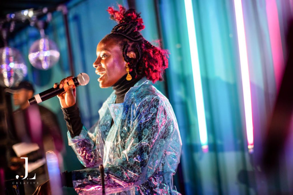 Musician performing at a DJ booth with neon lighting, corporate event photography London.