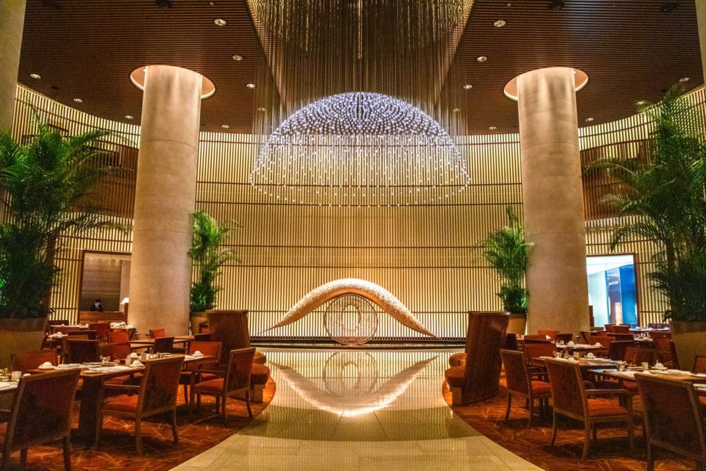 Luxury hospitality photography of a stunning, modern hotel lobby and dining area with architectural lighting.