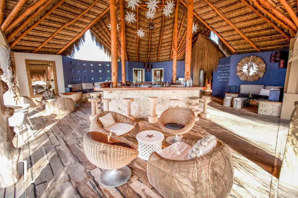 Luxury hospitality photography of a stylish beach bar with wicker seating and an elegant rustic aesthetic.