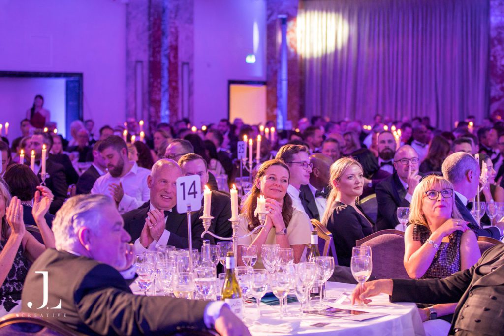 VIP event photography of a candlelit gala dinner with guests in elegant evening wear at a high-end venue.