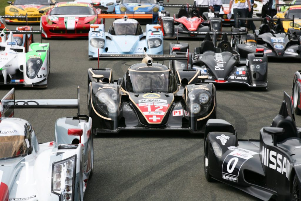 Luxury brand photography of high-performance race cars lined up on the track at an exclusive automotive event.