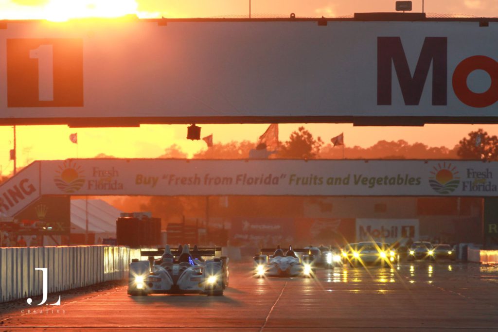 Experiential travel photography captures race cars driving into a golden sunset during an elite automotive race.