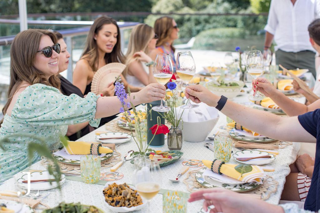 Guests raising glasses for a celebratory toast at a stylish outdoor luxury retreat lunch.