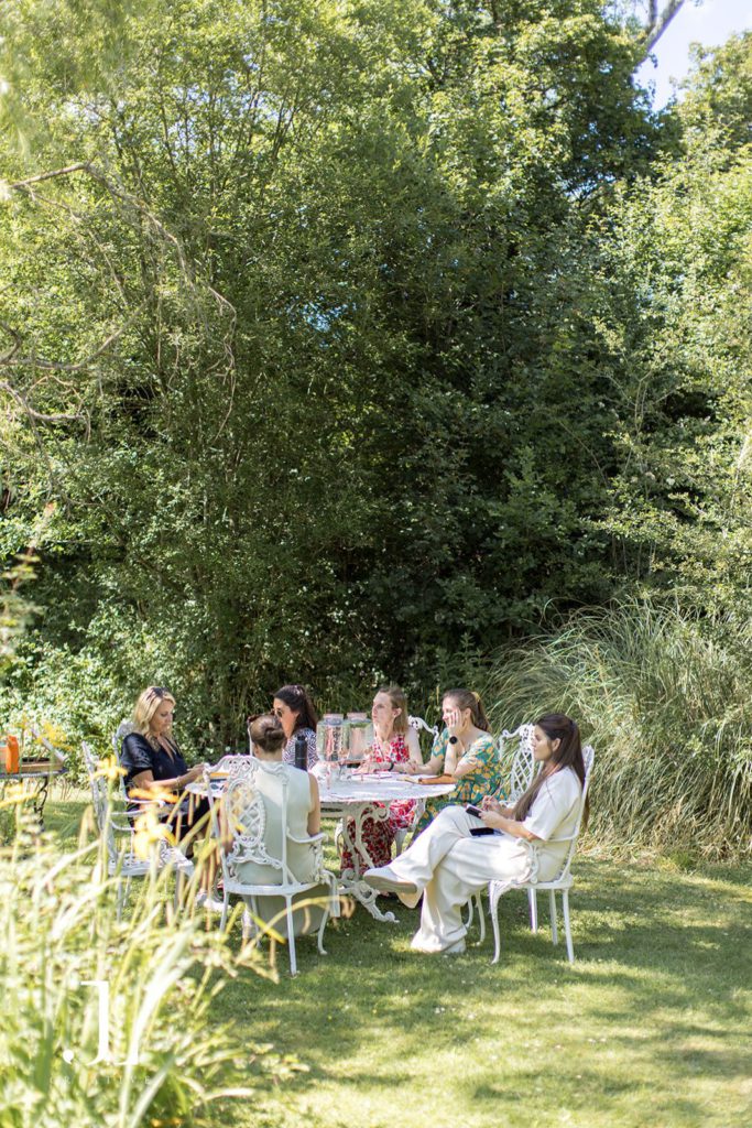 Private event photography of a group of women in stylish attire enjoying a sun-drenched outdoor retreat.