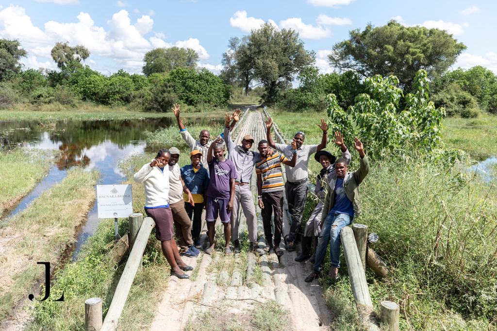Daunara Safari Camp staff waving on the wooden bridge, showcasing luxury hospitality photography in Botswana.