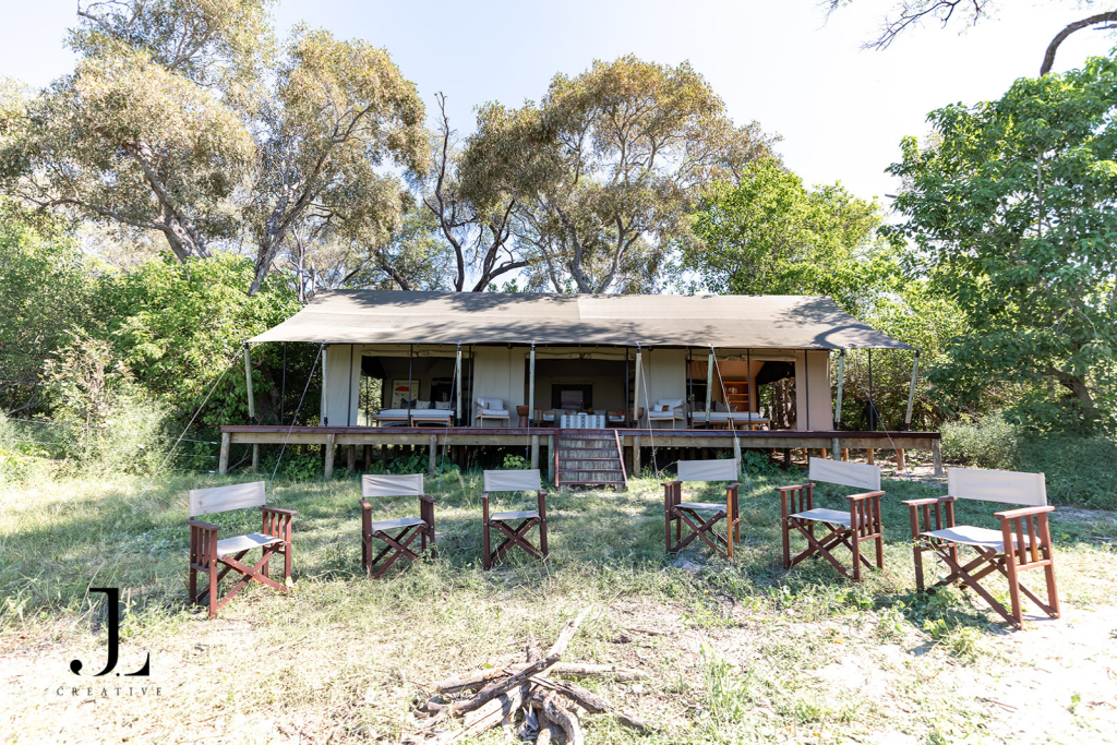 Outdoor fire pit lounge area in front of tented suite, featuring safari camp photography Botswana.