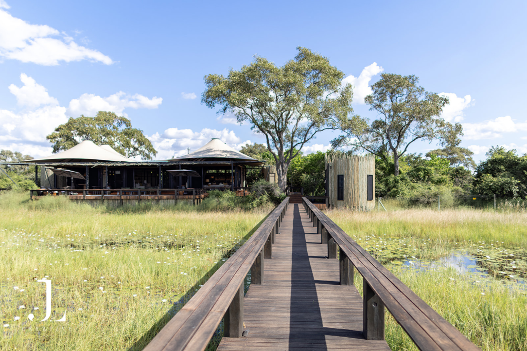 Wooden boardwalk leading to main lodge over wetland, captured for luxury safari lodge photography in Botswana.