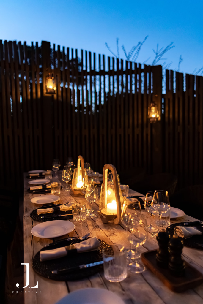 Candlelit alfresco dinner table setup at twilight, highlighting luxury hospitality photography in Botswana.